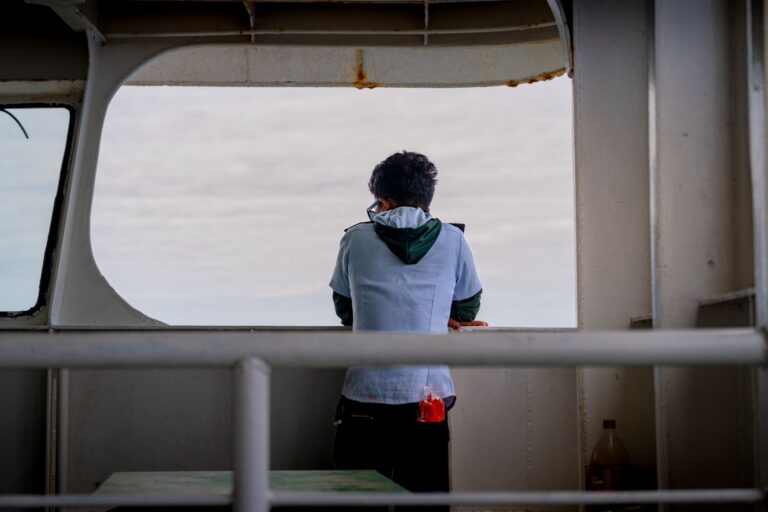 A Shipping crew member observing vessel operations from the ship's deck during an onboard inspection.